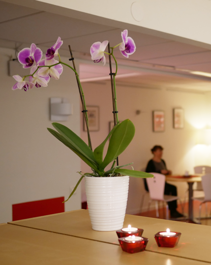 Kundreferenser - Incognito: Orkidé med tre små ljus. En kvinna sitter i bakgrunden